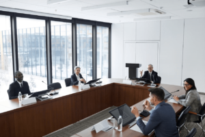 A business meeting with five professionals discussing KPIs around a conference table in a modern office space.