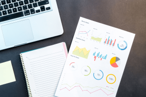 Photo of a laptop, a notebook and a sheet with different types of data visualizations