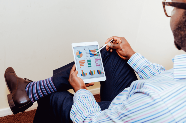 Man with colorful socks uses a tablet to analyze KPIs on a dashboard.