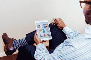 Man with colorful socks uses a tablet to analyze KPIs on a dashboard.